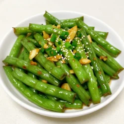 - 1 pound fresh green beans, trimmed Fresh green beans are the star of this dish. Choose bright green beans with a firm texture. Trim the ends to make them ready for cooking. Rinse them under cool water for a clean start. - 4 cloves garlic, finely minced - 1 tablespoon fresh ginger, finely grated - 2 tablespoons sesame oil - 1 tablespoon low-sodium soy sauce - 1 tablespoon chili garlic sauce - 1 teaspoon granulated sugar - 1 tablespoon rice vinegar Aromatics like garlic and ginger add a punch of flavor. Mince the garlic finely and grate the ginger well. They will release their bold flavors when sautéed. The sesame oil gives a rich taste. The soy sauce and chili garlic sauce bring both saltiness and heat. Sugar helps balance the heat, while rice vinegar adds a hint of tang. - 2 green onions, chopped (scallions) - Sesame seeds, for garnish Chopped green onions add freshness and color. Sprinkle sesame seeds on top for crunch and visual appeal. These garnishes elevate the dish, making it look and taste even better. {{ingredient_image_2}} Start by rinsing 1 pound of fresh green beans under cool water. This step removes any dirt. Next, trim the ends with a sharp knife. This makes them ready for cooking. Properly prepped beans will cook evenly and taste great. In a large skillet or wok, heat 2 tablespoons of sesame oil over medium-high heat. Wait until the oil shimmers a bit. Then, add 4 cloves of minced garlic and 1 tablespoon of finely grated ginger. Sauté these for about 30 seconds. Stir them continuously. You want them fragrant, not burnt! Now, raise the heat to high. Add the trimmed green beans to the skillet. Stir-fry for 4 to 5 minutes. The beans should turn vibrant green and be tender-crisp. While they cook, mix together 1 tablespoon of low-sodium soy sauce, 1 tablespoon of chili garlic sauce, 1 teaspoon of sugar, and 1 tablespoon of rice vinegar in a small bowl. Pour this sauce over the beans. Toss them well to coat. Stir-fry for another 2 minutes. This warms everything through. Finally, sprinkle chopped green onions and sesame seeds on top. Serve the dish hot. Enjoy! To get that perfect crunch, start with fresh green beans. Look for beans that are bright and firm. Trim the ends before cooking. Sauté them in hot sesame oil for a quick stir-fry. Stir often to keep them crisp. A good rule is to cook them for 4-5 minutes. They should look vibrant and tender but not mushy. You can boost flavor with a few tweaks. Add more garlic if you love it. A splash of lime juice gives a fresh zing. Consider adding red pepper flakes for extra heat. Toss in some sliced bell peppers or carrots for color and taste. Mixing in sesame seeds adds a nice crunch too. Avoid overcooking your green beans. They lose their bright color and crispness. Don’t skip the sauce mix; it ties all flavors together. Stir-frying on too low heat makes the beans soggy. Also, remember to stir continuously when cooking garlic and ginger to prevent burning. Pro Tips Choose Fresh Beans: Select bright green beans that are firm and crisp for the best flavor and texture. Adjust Spice Level: Customize the heat by adding more or less chili garlic sauce according to your preference. Use High Heat: Stir-frying on high heat ensures that the green beans remain vibrant and retain their crunchiness. Garnish for Flavor: Don't skip the green onions and sesame seeds; they add a fresh crunch and enhance the dish's visual appeal. {{image_4}} You can boost the protein in your stir fry. Tofu is a great choice. Just press it to remove water. Cut it into cubes and fry it with the garlic and ginger. Chicken works well, too. Cut it into thin strips and add it after the garlic. For shrimp, add them after the green beans. Cook until they turn pink. Each option adds flavor and makes the dish heartier. If you love heat, add more chili garlic sauce. A pinch of red pepper flakes works, too. Start with a little and taste as you go. For milder flavor, use less chili sauce. You can also add a squeeze of lime juice. The acidity can balance the heat. Adjusting spice makes the dish your own. Feel free to swap in other veggies. Bell peppers add color and sweetness. Broccoli provides crunch and nutrients. Snow peas or carrots can bring a nice crunch, too. Just cut them into similar sizes as the green beans. This keeps everything cooking evenly. Mixing veggies not only adds flavor but also makes the dish more colorful and fun. Store your spicy garlic green beans in an airtight container. This keeps them fresh longer. Place them in the fridge within two hours of cooking. They can last for about 3-4 days. Make sure to let them cool down before sealing the container. This helps reduce moisture buildup. When reheating, use a skillet or a microwave. For the skillet, add a splash of water or oil to keep them moist. Heat over medium until warm. If using a microwave, cover the bowl with a damp paper towel. Heat in short bursts to avoid overcooking. This keeps them tasting fresh and crunchy. You can freeze these green beans if you want to save some for later. Allow them to cool completely. Place them in a freezer-safe bag or container. Remove as much air as possible before sealing. They can stay frozen for up to three months. To enjoy, thaw them in the fridge overnight before reheating. Yes, you can use frozen green beans. They are convenient and save time. Just skip the rinsing step. When using frozen beans, add them straight to the hot skillet. Stir-fry them for about 6-8 minutes. This will help them cook through. They may be softer than fresh beans, but they still taste great in the dish. You can pair this dish with many tasty options. Steamed rice is a classic choice. Noodles also work well. If you want extra protein, try adding tofu, chicken, or shrimp. A light salad can complement the dish, too. I love serving it alongside a warm bowl of miso soup. Making the Spicy Garlic Green Bean Stir Fry vegan is easy! Simply replace the low-sodium soy sauce with a vegan alternative. You can also use tamari for a gluten-free option. Ensure that your chili garlic sauce is vegan-friendly as well. This way, you keep all the bold flavors while sticking to a plant-based diet. This blog has given you key steps to make a great green bean stir fry. We covered fresh green beans, aromatics, and tasty sauces. You learned how to prep, sauté, and cook everything perfectly. Tips on getting crispness and avoiding common mistakes will help too. You can add protein or adjust spice for more flavor. Lastly, proper storage keeps leftovers fresh. Enjoy making this dish your own!